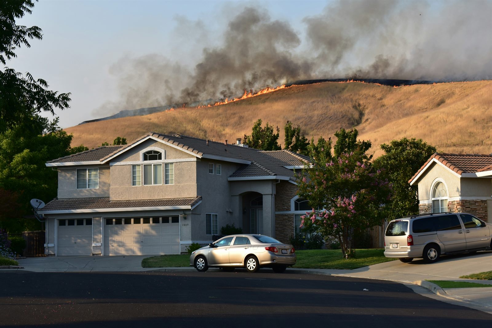 Homeowner standing in front of a suburban house reading a non-renewal letter from an insurance company