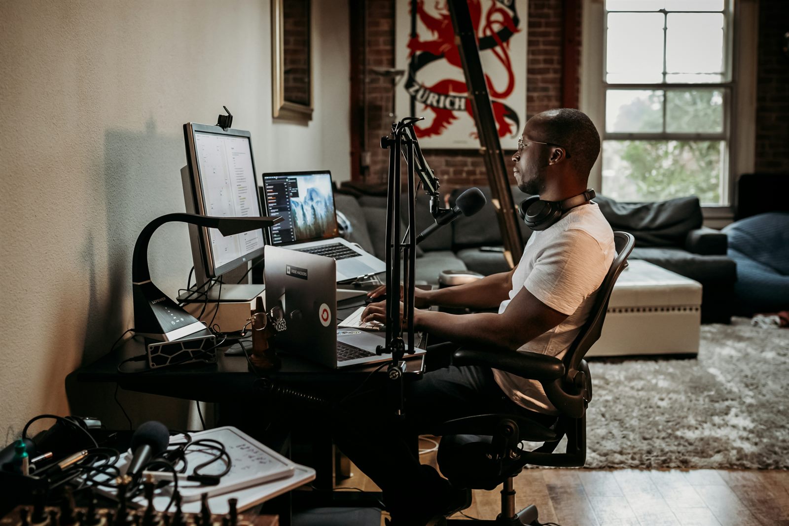Person building a creative portfolio on a laptop, surrounded by sketchbooks and mood boards