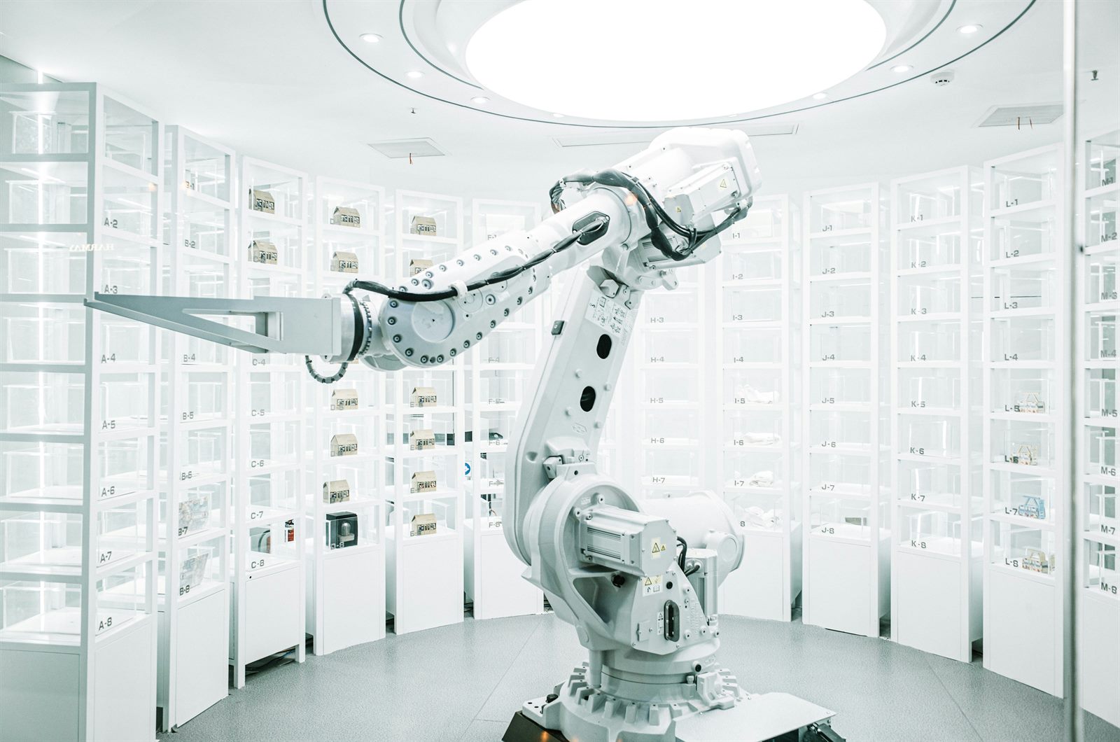 A robotic arm working alongside a human on a factory floor, both illuminated by blue light