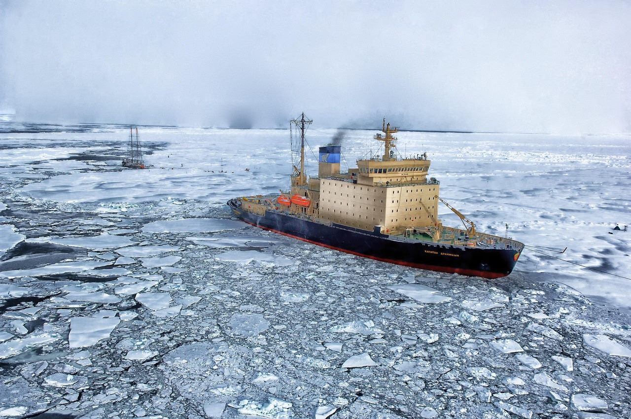 A Russian nuclear-powered icebreaker cutting a channel through sea ice under a low Arctic sun