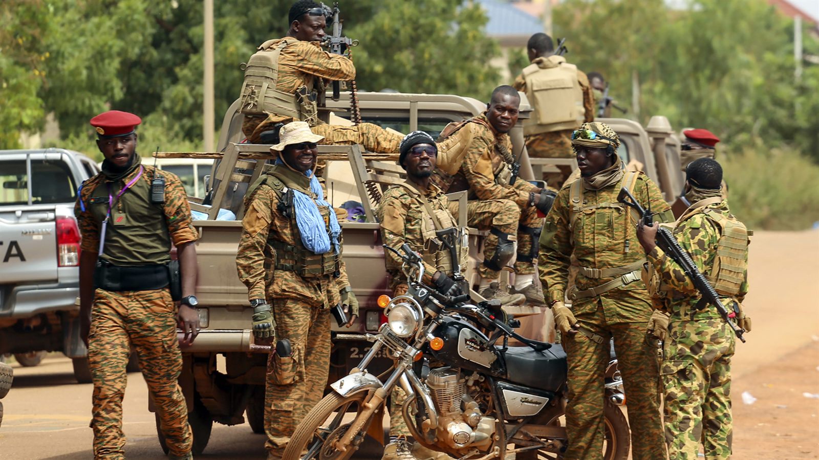 Soldiers in fatigues standing guard on a dusty road at the edge of a Sahel town