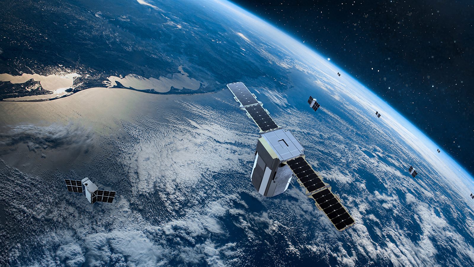 A communications satellite with gold solar panels orbiting above the curve of the Earth