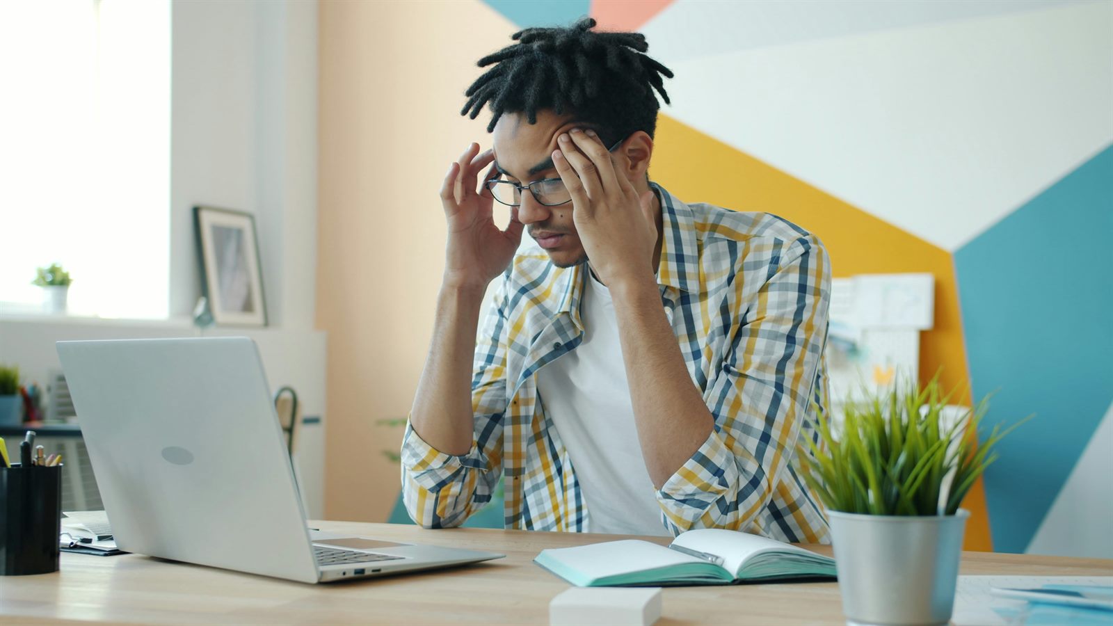 Young professional at a kitchen table reviewing financial statements, student loan paperwork visible