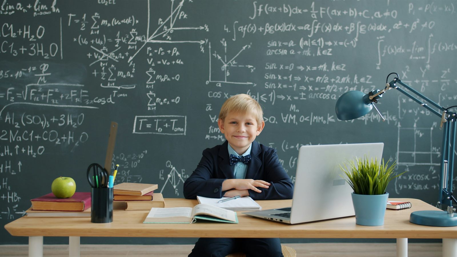 A teacher kneeling beside a student at a tablet, engaged in conversation rather than instructing from the front of a room