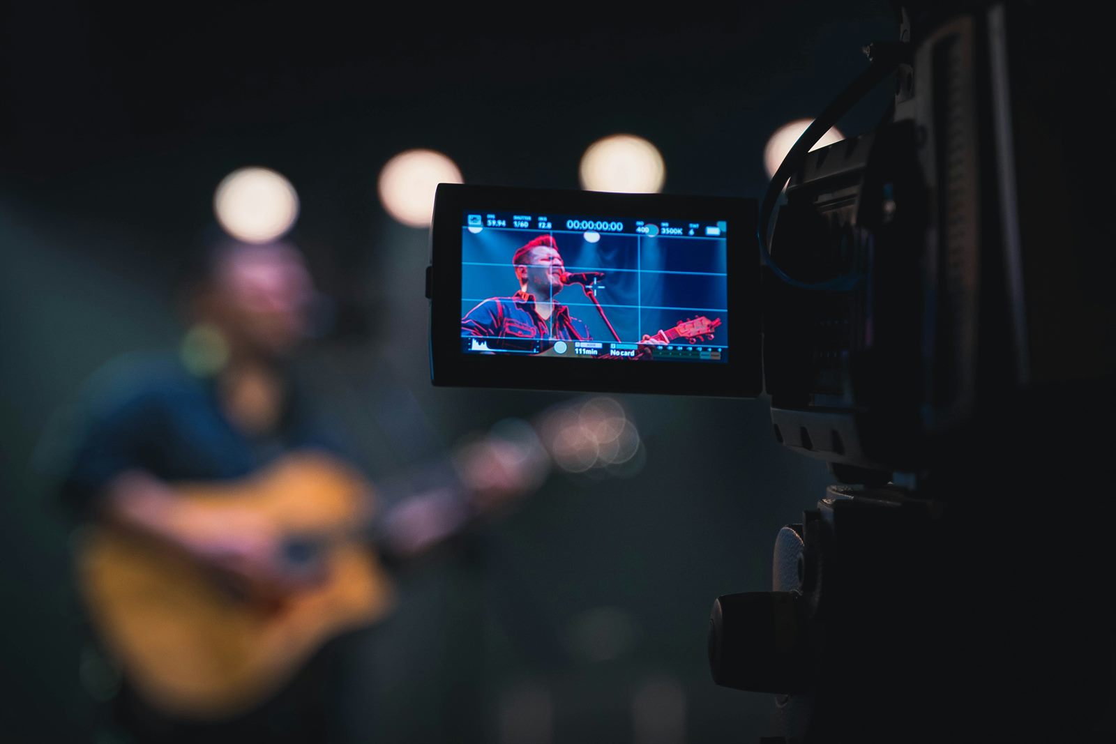 Fan at home watching a live stadium concert stream in a headset while friends watch on a large screen behind them