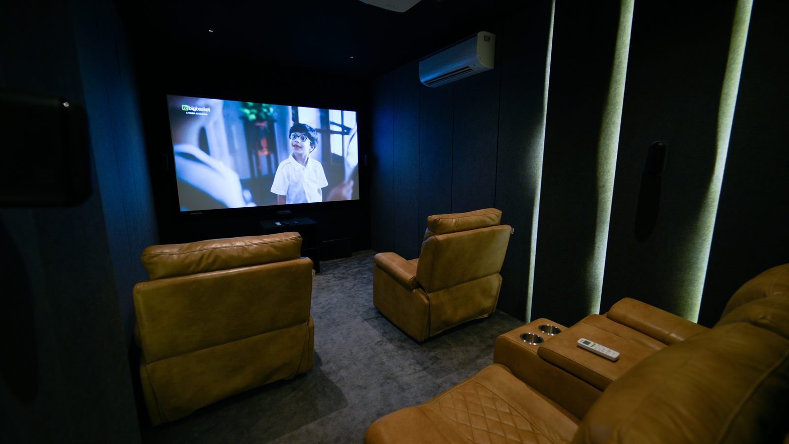 Server delivering food to moviegoers seated in leather recliners inside a dine-in cinema