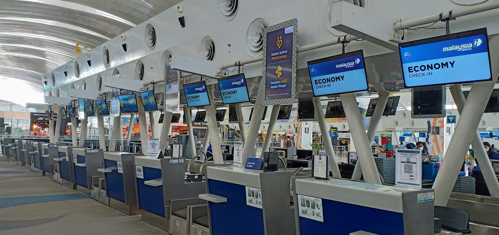 Traveler walking through an open biometric security corridor at an airport while sensors scan without stopping them