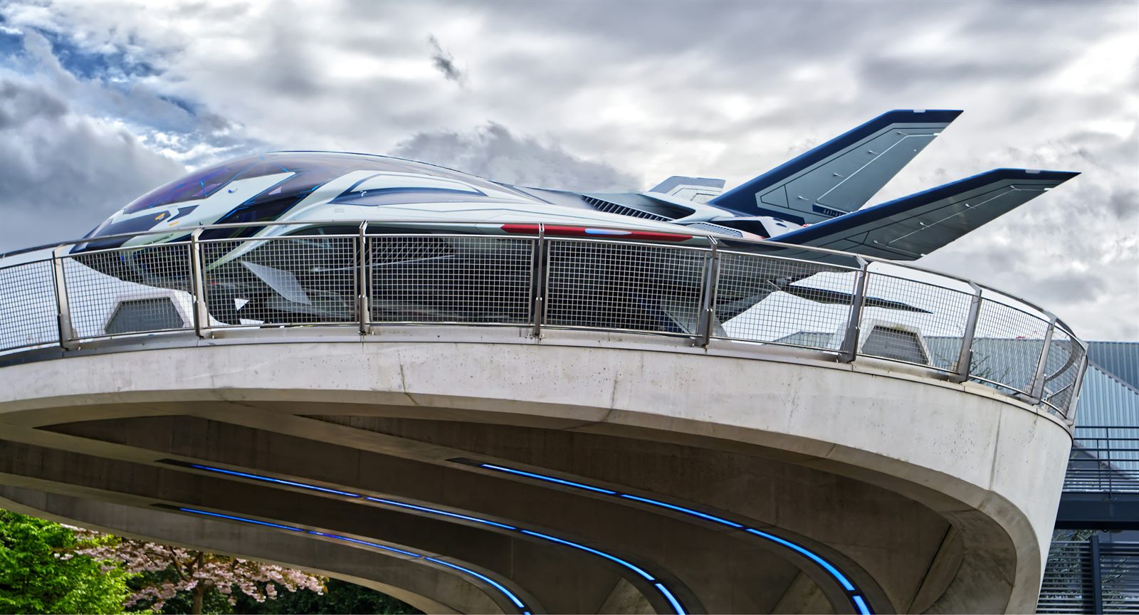 An electric air taxi with multiple rotors lifting off from a rooftop vertiport above a city skyline
