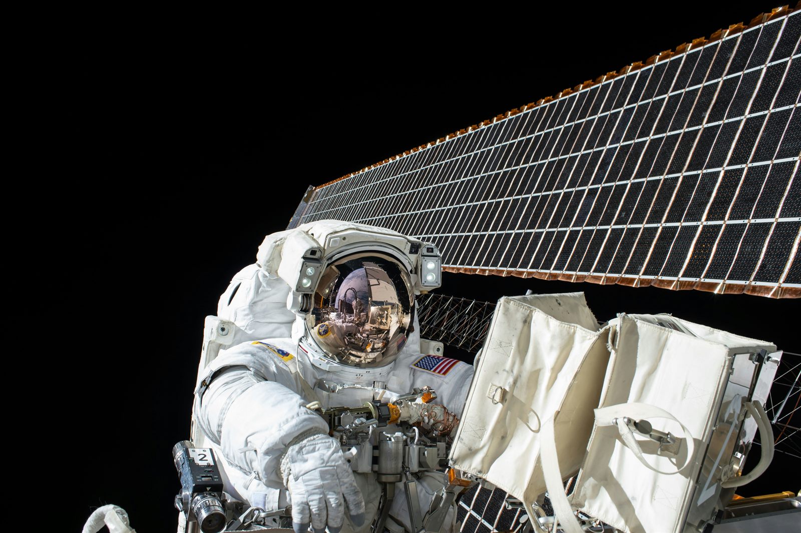 A vast orbital solar array unfolding in space with Earth's curve and the sun in the background