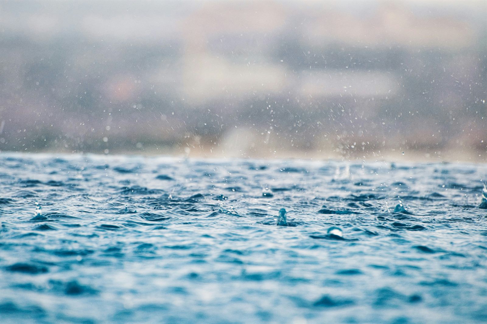 A reservoir dam releasing water ahead of an incoming storm under a heavy grey sky
