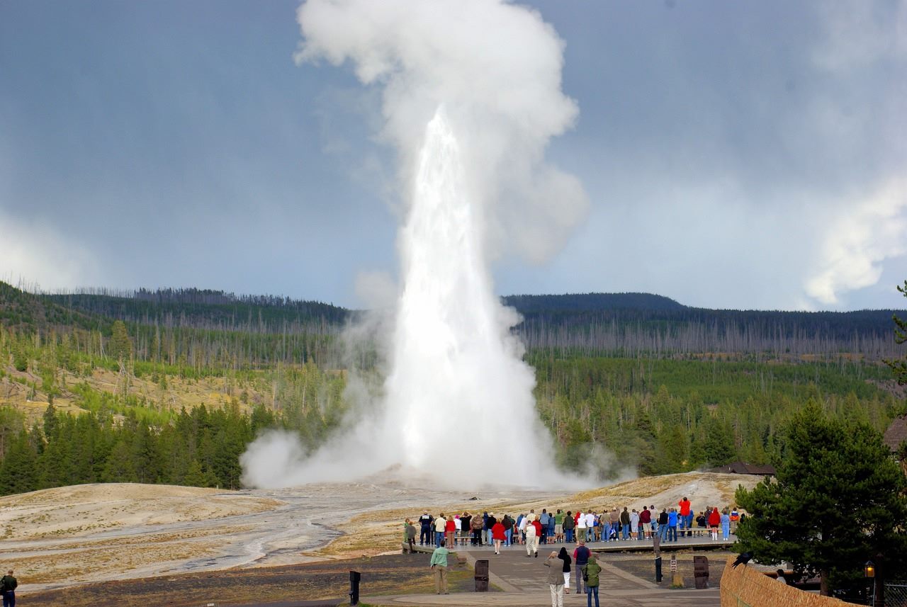 Steam rising from a geothermal power plant set against a landscape of hot springs and rugged Western terrain